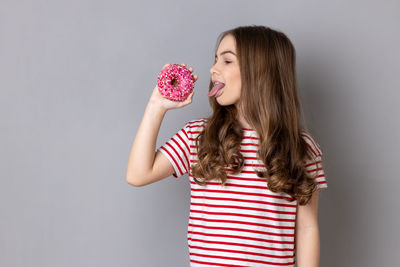 Portrait of woman holding heart shape against white background