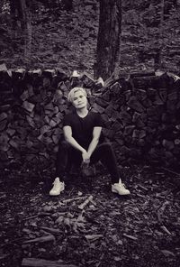 Portrait of woman sitting on land in forest