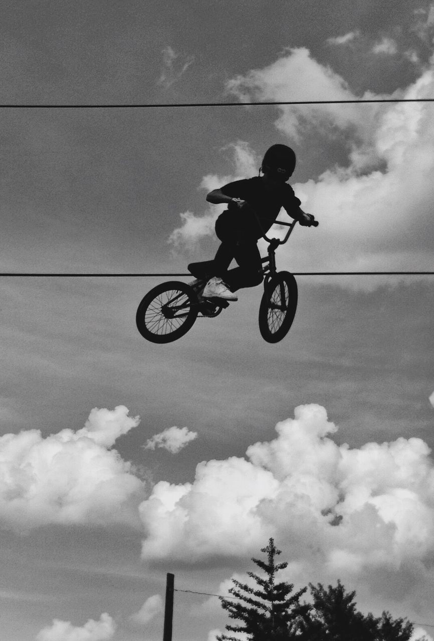 transportation, low angle view, bicycle, sky, men, mode of transport, leisure activity, lifestyles, extreme sports, riding, cycling, cloud - sky, stunt, silhouette, full length, adventure, sport, motion