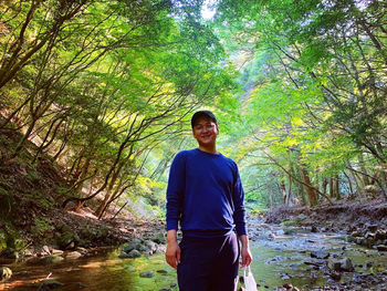 Portrait of young man standing in forest
