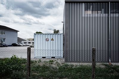 Plants growing on field by building against sky