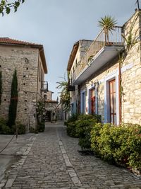 Narrow alley amidst houses and buildings against sky