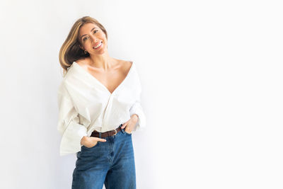 Portrait of young woman standing against white background