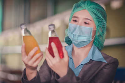 Close-up of woman wearing mask inspecting drinks in factory