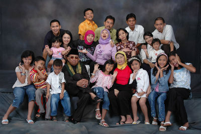 Multi-generation family sitting against gray background