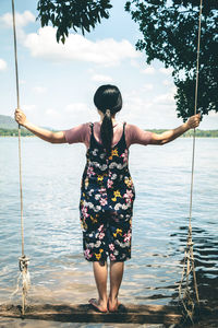 Rear view of woman swinging by lake