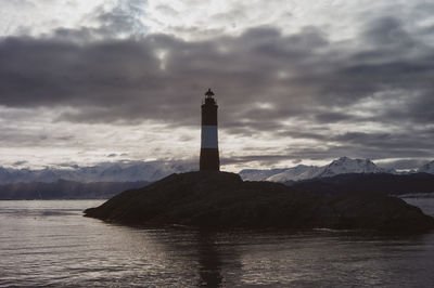 Lighthouse by sea against sky