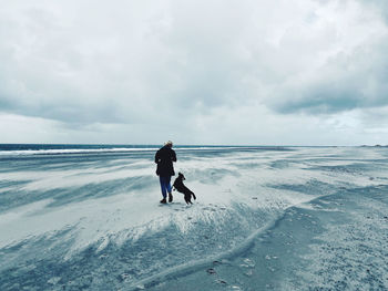 Rear view of men walking on street amidst sea against sky