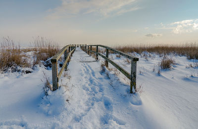 Snow on landscape against sky during winter