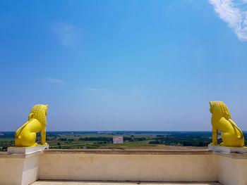 Statue by sea against blue sky