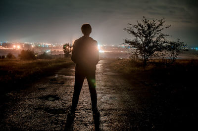 Rear view of silhouette man standing on field at night