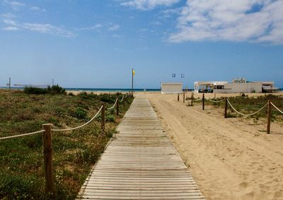 Boardwalk leading towards beach against sky