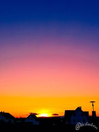 Silhouette buildings against clear sky at sunset