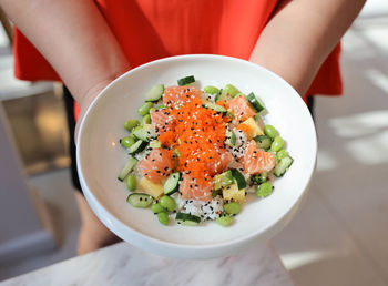 High angle view of person holding salad in plate on table