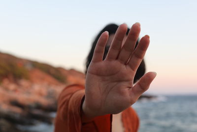 Close-up of hand against sky during sunset