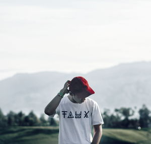 Rear view of man standing on field against sky