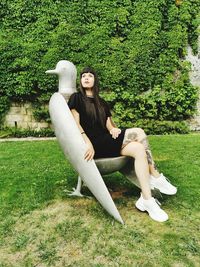 Portrait of young woman sitting on pigeon sculpture