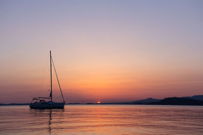 Sailboat in sea against sky during sunset