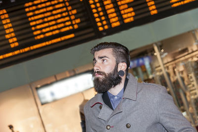 Hipster businessman consult the board of timetable trains