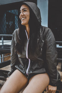 Smiling young woman looking away while sitting on bench