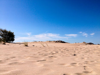 Sand dunes in desert against blue sky