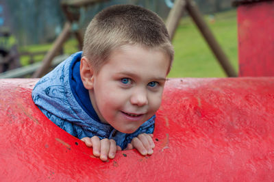 Close-up portrait of boy in red play equipment at playground