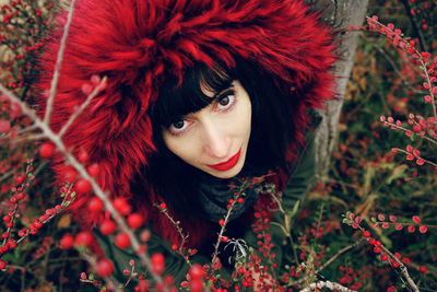 High angle portrait of woman wearing warm clothing amidst red berries on plants