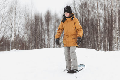 Cute teenage girl rides a snowskate in a winter park, healthy lifestyle