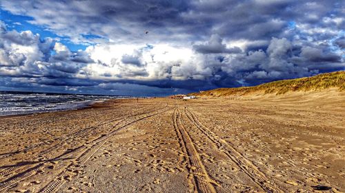 Scenic view of beach against cloudy sky