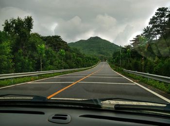 Road leading towards mountain seen through car windshield