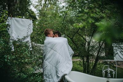 Couple with towel standing against trees