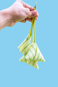 Close-up of hand holding ice cream against blue background