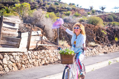 Cheerful woman riding bicycle on road