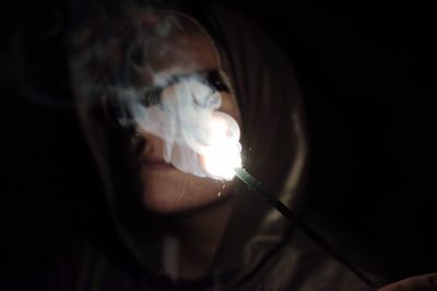 Close-up of young woman holding illuminated lighting equipment