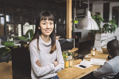 Portrait of smiling businesswoman with arms crossed at workplace