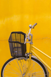 Bicycle parked against yellow wall