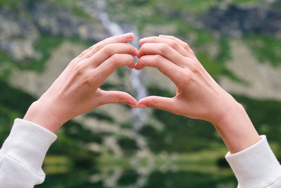 Close-up of hand making heart shape outdoors