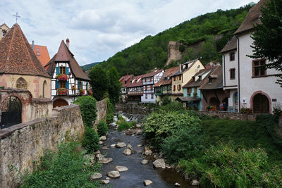 Houses by buildings in town against sky