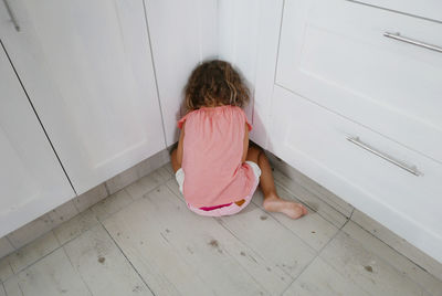 Rear view of girl hiding in kitchen