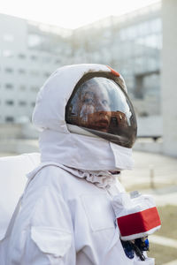 Female astronaut in space suit looking away in city