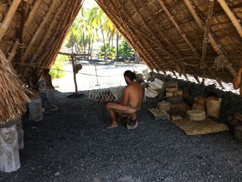 Full length of shirtless man sitting outdoors