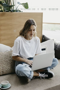 Woman concentrating while using laptop sitting on sofa
