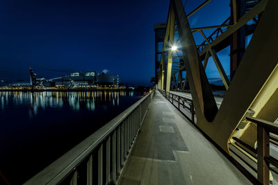 Illuminated bridge over river against sky at night