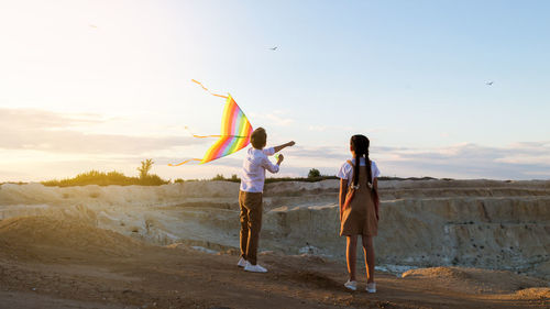 Children with a kite on a high rock near canyon in rays at sunset.