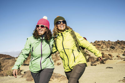 Smiling young women looking away against clear sky