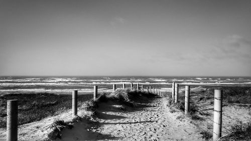 Wooden posts on beach against sky