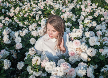 Portrait of young woman standing amidst flowers