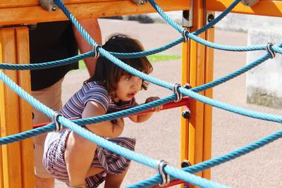 Low angle view of girl playing on rope in playground