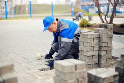 Bricklayer lays paving slabs outside. working man performs landscaping. builder lays out sidewalk