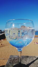 Close-up of beer glass against blue sky